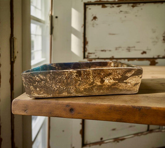 A handmade rectangular ceramic vase with textured earthy glaze, placed on a wooden table in warm natural light.